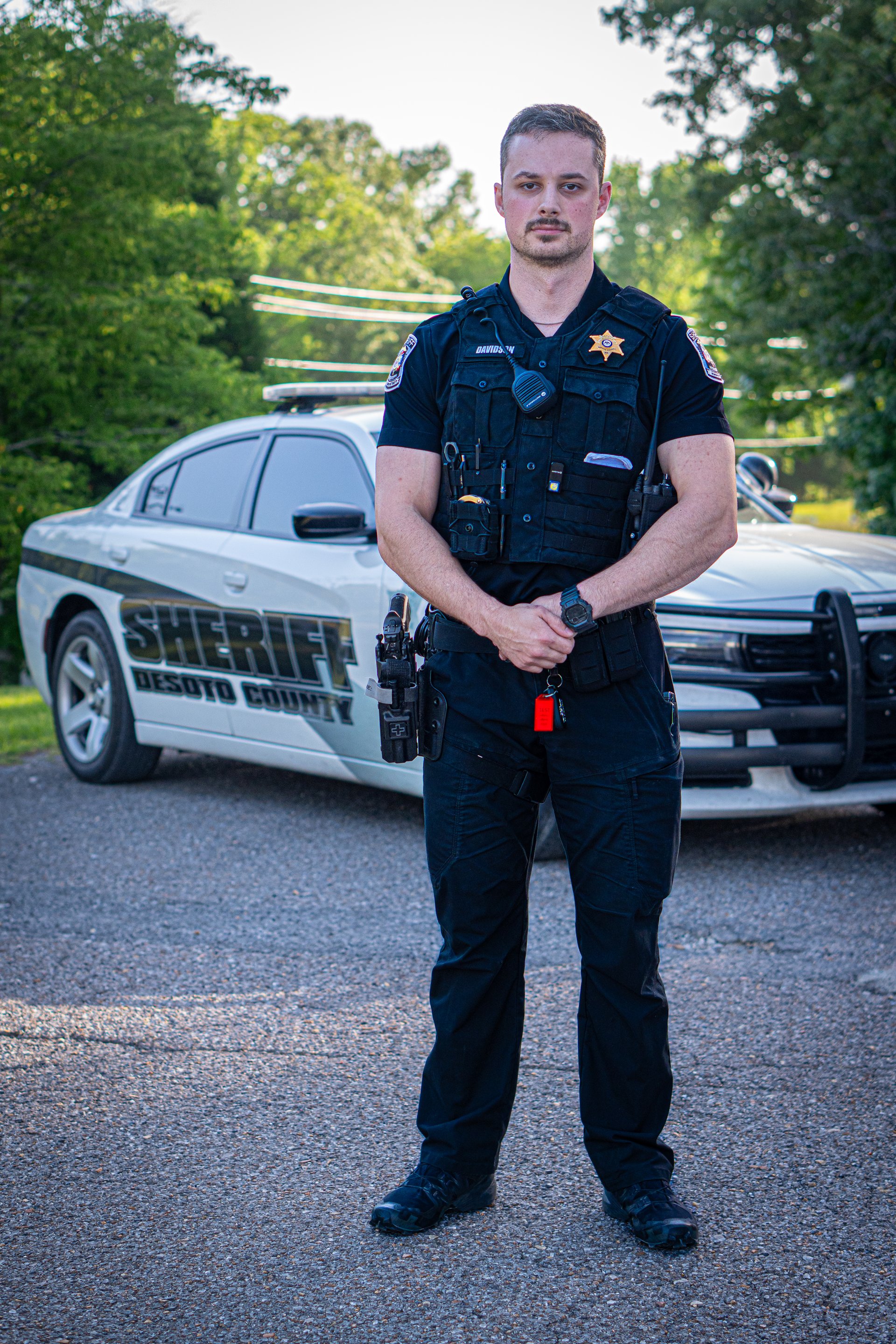 A DeSoto County deputy standing in front of a marked patrol vehicle