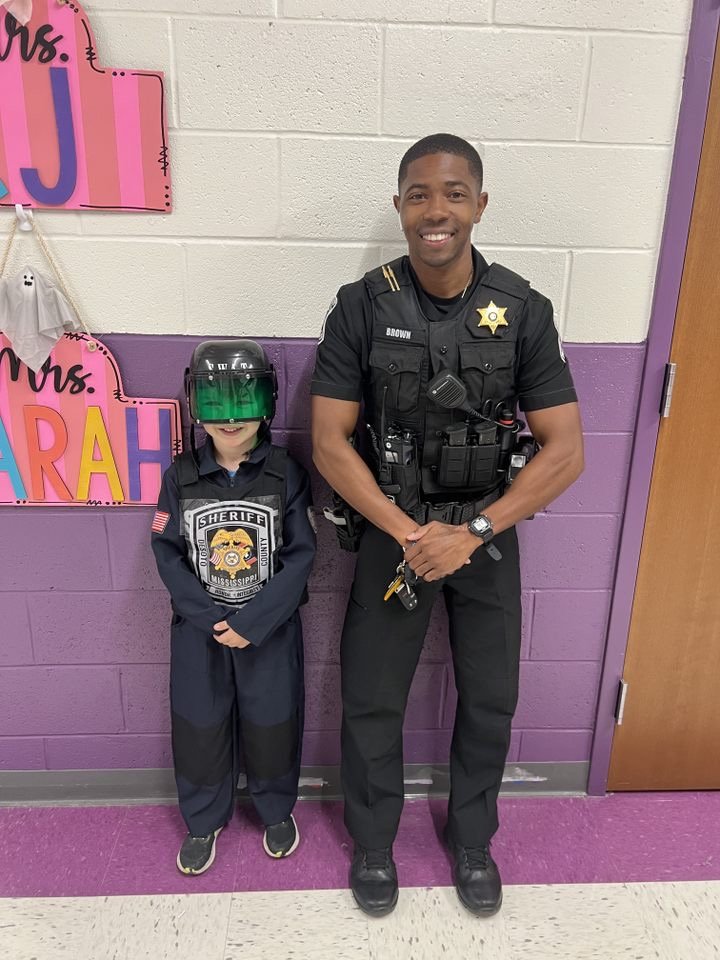 A DeSoto County deputy standing with a young student wearing a junior Sheriff's Office uniform at school