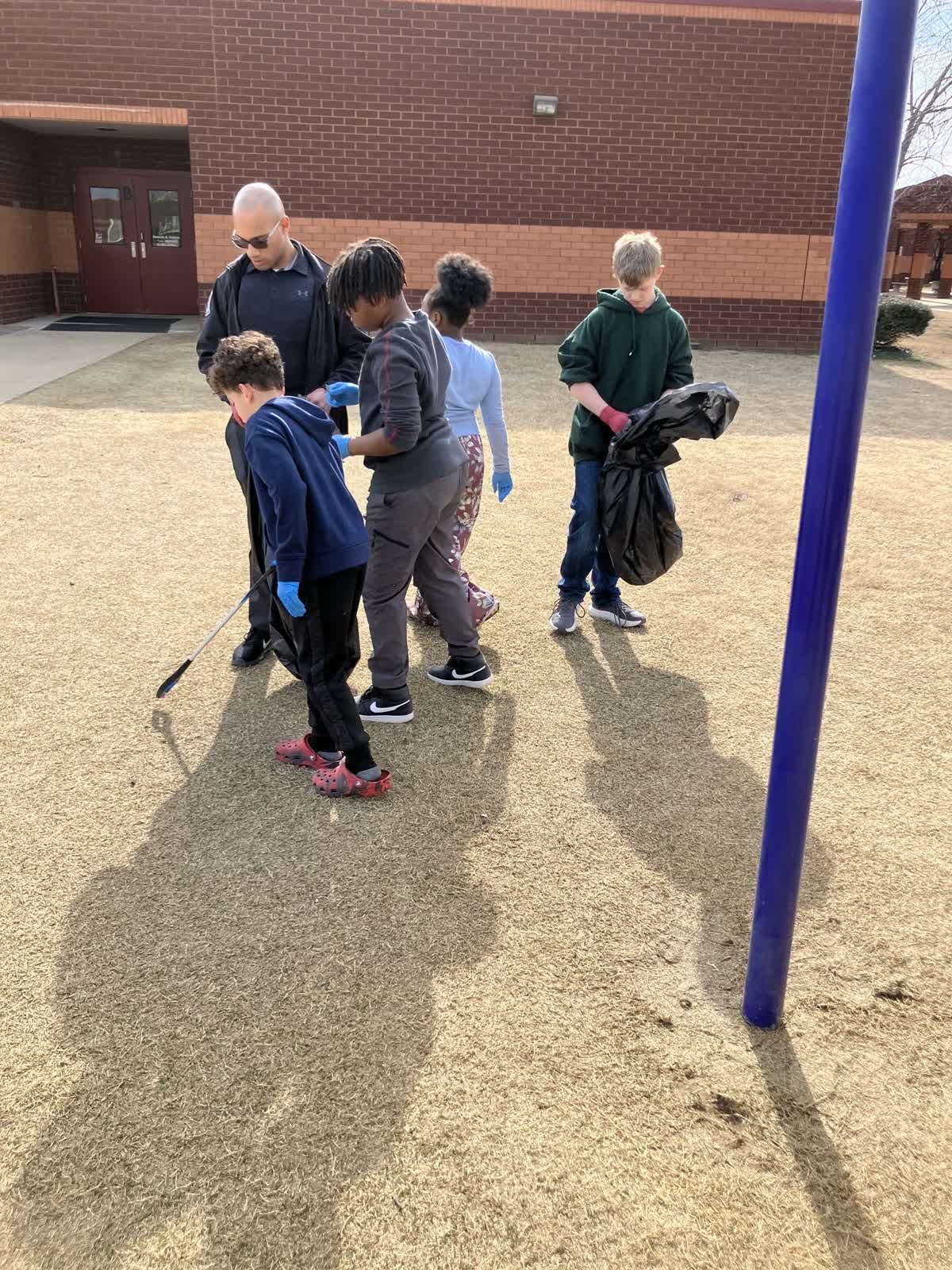 A DeSoto County School Resource Officer supervising students during a campus cleanup project